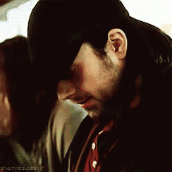 a man with a beard wearing a hat and a jacket .