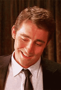 a man wearing a suit and tie is smiling with his eyes closed .
