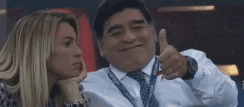 a man in a suit and tie is giving a thumbs up to a woman .