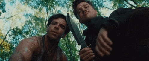 two men are standing next to each other holding knives in their hands .