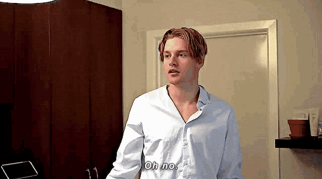 a man in a white shirt is standing in front of a door and saying oh no