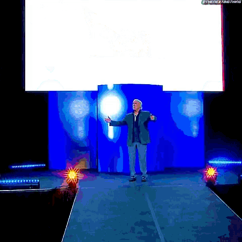 a man stands on a stage with his arms outstretched in front of a screen that says @thenextbigthing