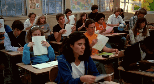 a group of students in a classroom with a map of the world on the wall behind them