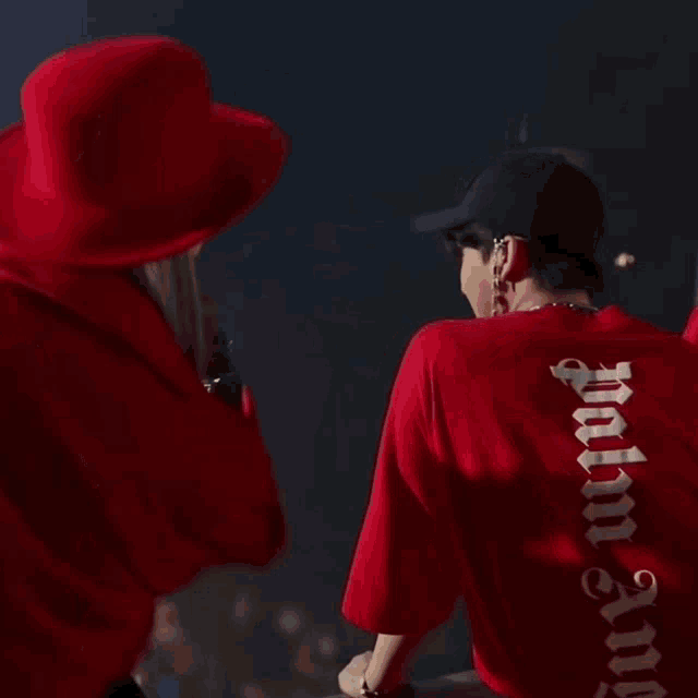 a man wearing a red shirt that says palm angels on it