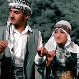 a man and a woman are holding hands in a forest .