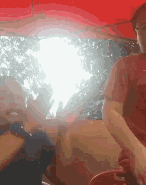 a man in a red shirt sits under an umbrella
