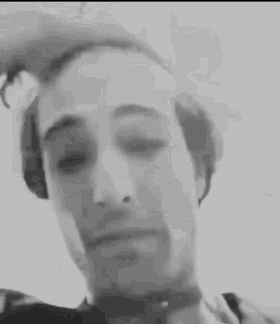 a close up of a man 's face in a black and white photo with his eyes closed .