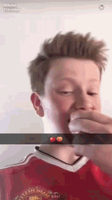 a boy wearing a red shirt that says manchester united