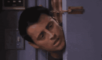 a man is peeking out of a door and making a funny face .