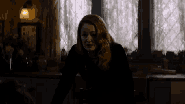 a woman in a dark room with a stained glass window
