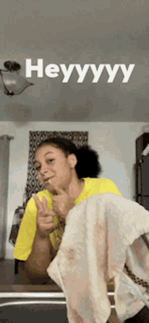 a woman in a yellow shirt is holding a towel and giving the thumbs up