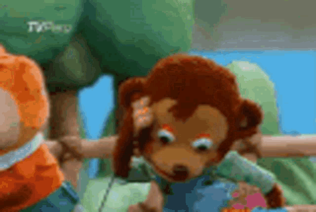 a stuffed monkey is standing next to another stuffed animal in a tv show .