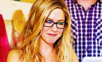 a woman wearing glasses is smiling while looking at a tablet .
