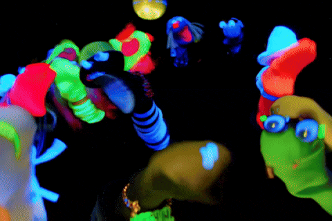 a group of glow in the dark puppets are dancing in a dark room