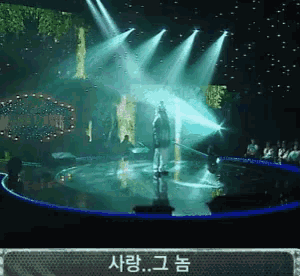 a woman singing on a stage with a sign that says " 사랑 " on it