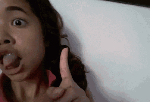 a girl is sticking her tongue out and giving a thumbs up sign