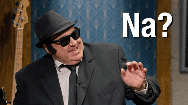 a man wearing sunglasses and a hat with the word na behind him