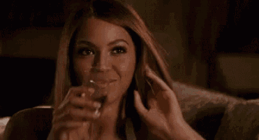 a woman is sitting on a couch drinking from a glass .