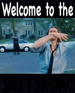 a man in a blue shirt and tie is dancing in front of a white car with the words welcome to the in white letters