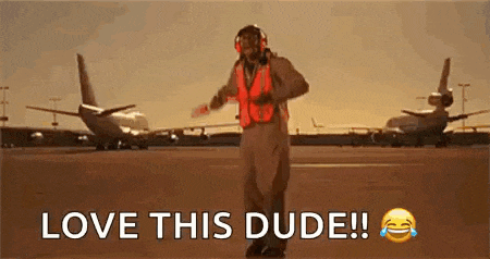 a man in a helmet and safety vest is dancing on an airport runway .