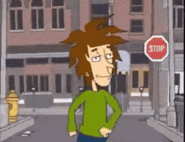 a man in a green sweater is standing in front of a stop sign