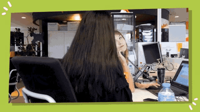 a woman sitting at a desk with a laptop and a bottle of water