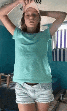 a girl wearing shorts and a blue shirt is standing in a room