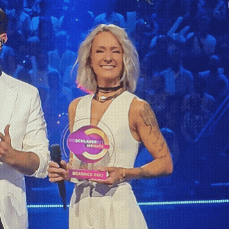 a woman in a white dress is holding a plaque that says beatrice egg