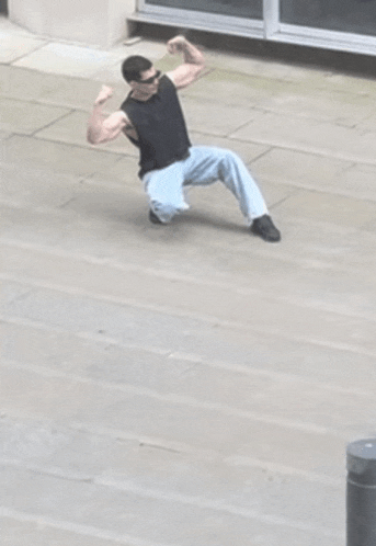 a man flexing his muscles while kneeling down on the ground
