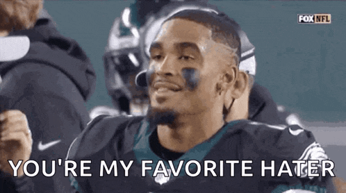 a football player is smiling and says `` you 're my favorite hater '' while sitting in the stands .