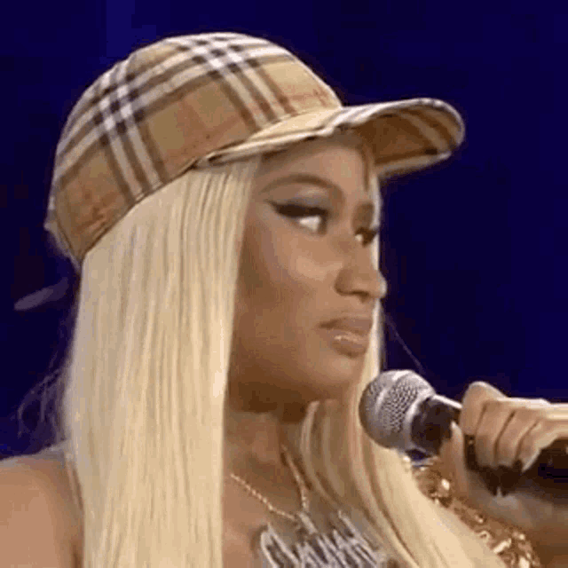 a woman wearing a hat is holding a microphone .