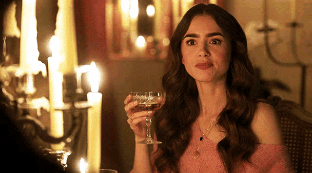a woman in a pink off the shoulder top holds a glass of wine