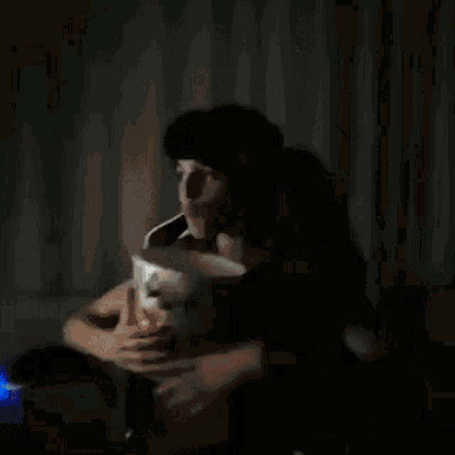 a person in a dark room is holding a white object over their head .