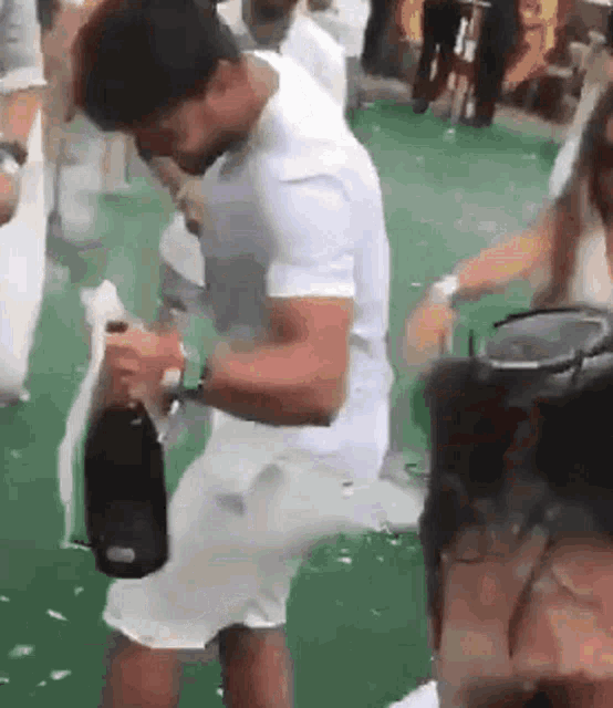 a man in white shorts is holding a bottle of champagne