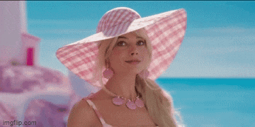 a woman wearing a pink hat and a pink necklace is standing on the beach .