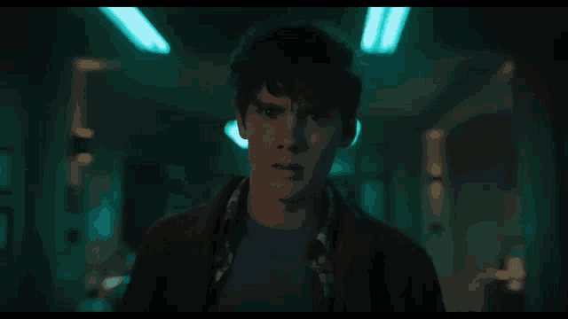 a young man is standing in a dark room with a blue light on the ceiling .