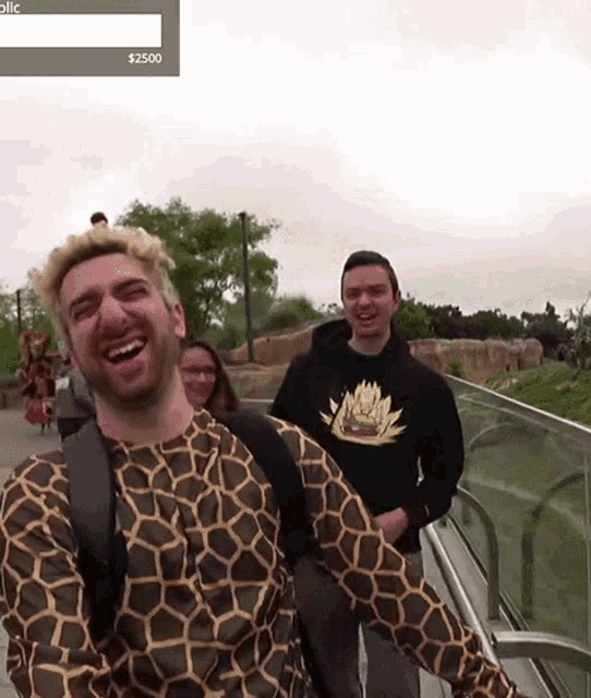a man wearing a giraffe shirt laughs while standing next to two other men