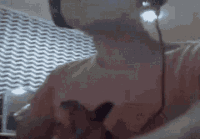 a person wearing headphones and a pink shirt is sitting in front of a wall with a chevron pattern