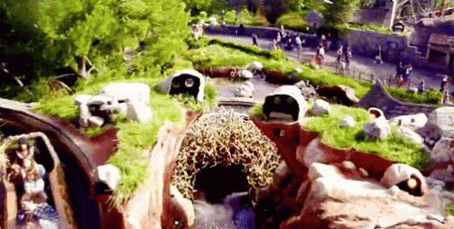 a roller coaster is going down a hill with a waterfall in the background .