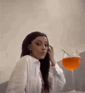 a woman is sitting at a table with a glass of wine and a straw in her mouth .