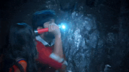 a man and a woman are fighting in a cave with a flashlight .