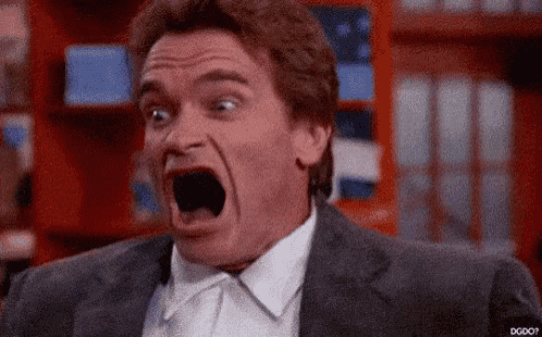 a man in a suit and tie is screaming with his mouth wide open .