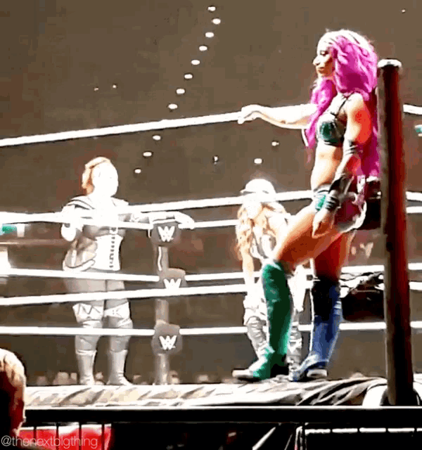 a woman with pink hair is standing in a wrestling ring with the letter w on the ropes