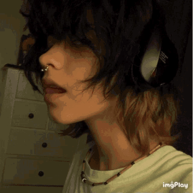 a girl with short hair is wearing headphones and a necklace .