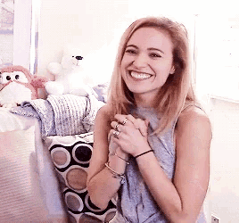 a woman is smiling while sitting on a couch in a room with stuffed animals .