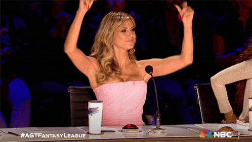 a woman in a pink dress is giving a thumbs up in front of a microphone on nbc