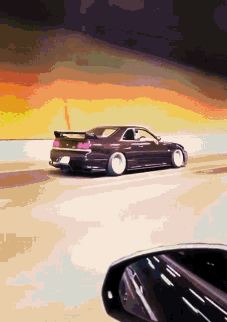 a car is driving down a road with a rear view mirror in the foreground