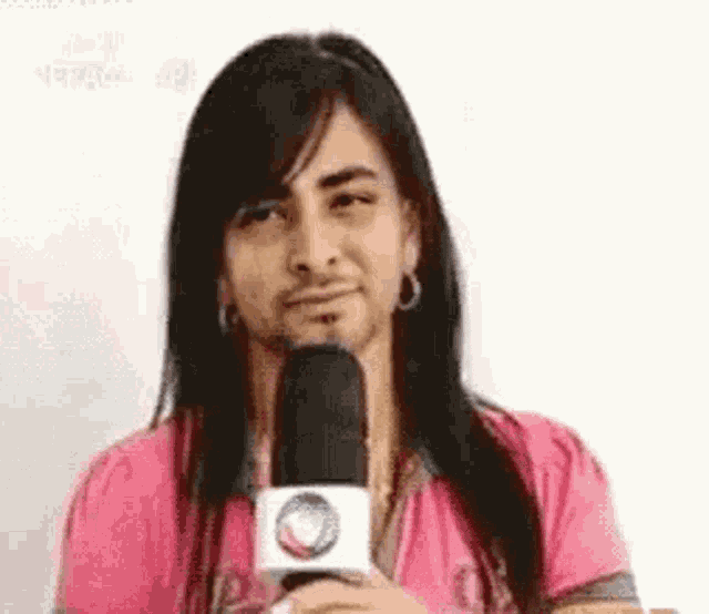 a man with long hair is holding a microphone in his hand .
