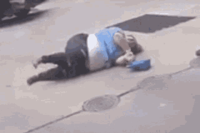 a man is squatting down on the sidewalk while holding a pair of shoes in front of a car .