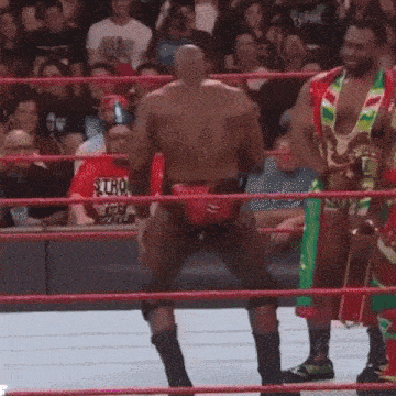a group of wrestlers are standing in a ring and one of them has a trophy in his hand .